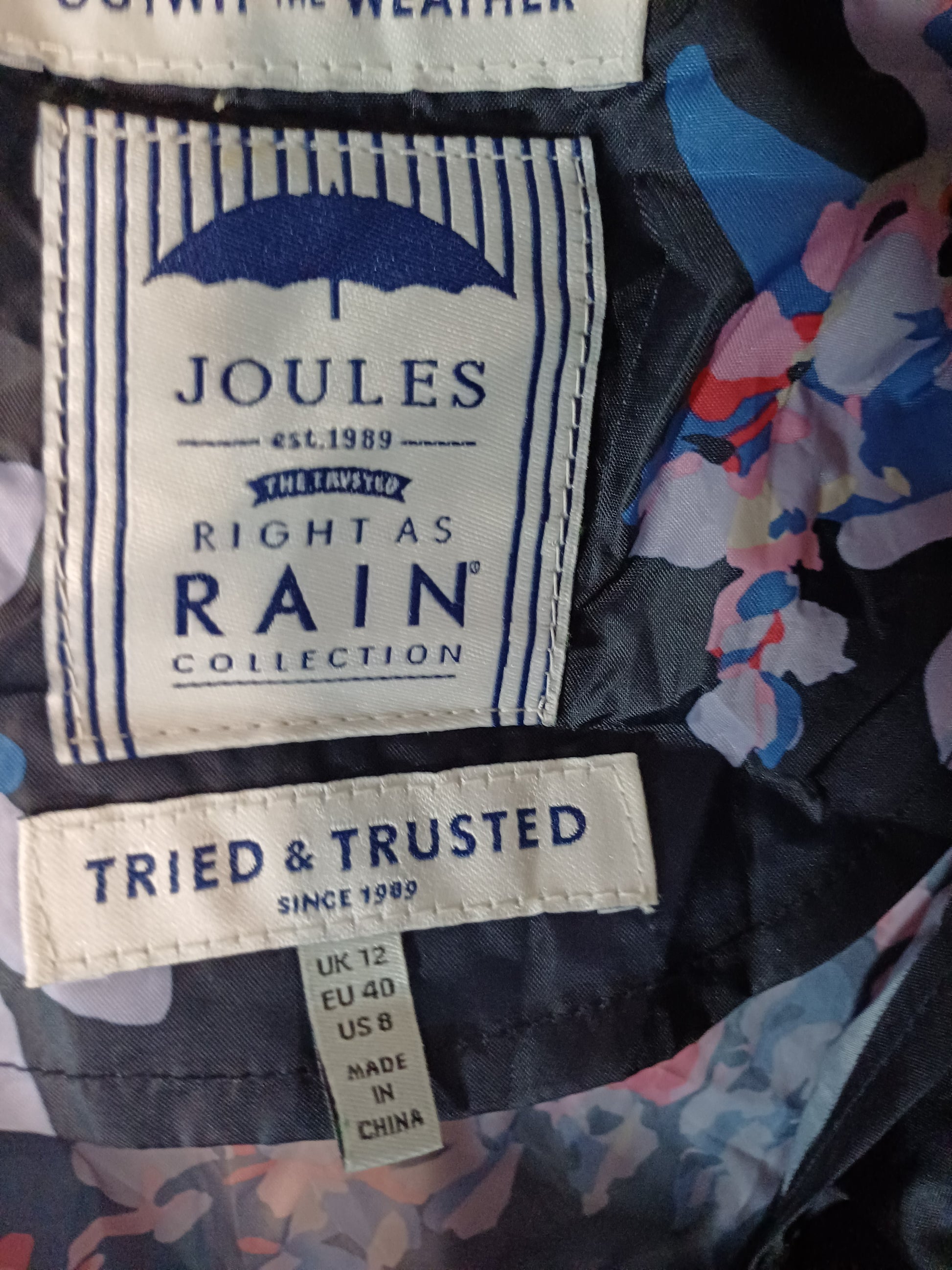 Close-up of Joules raincoat labels with floral pattern in the background