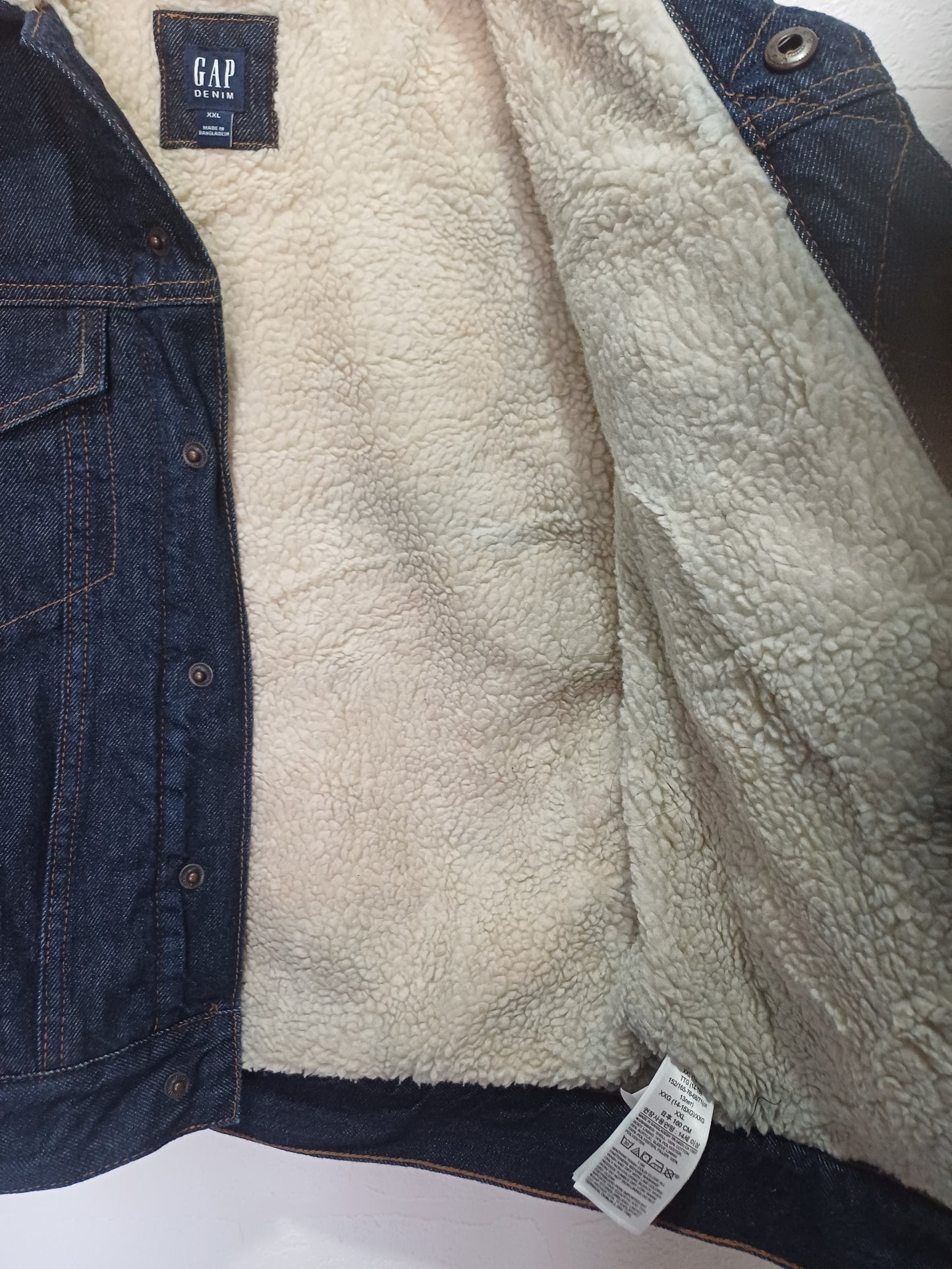 Close-up of a denim jacket with fleece lining and Gap brand tag.
