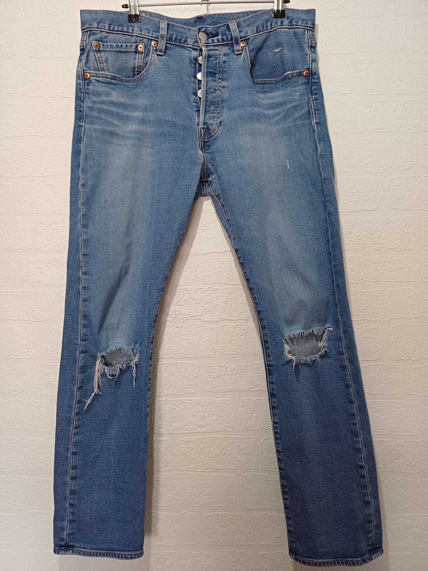 Pair of blue jeans with slight distressing on a light background