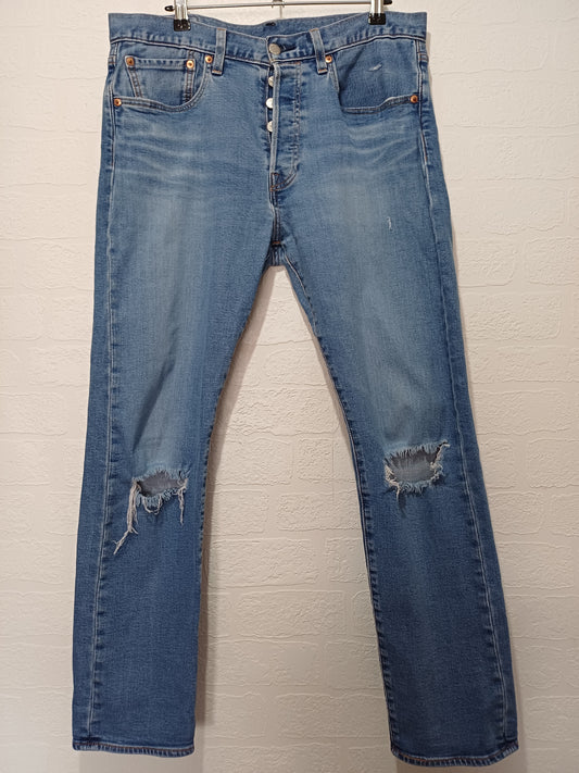 Pair of blue jeans with slight distressing on a light background